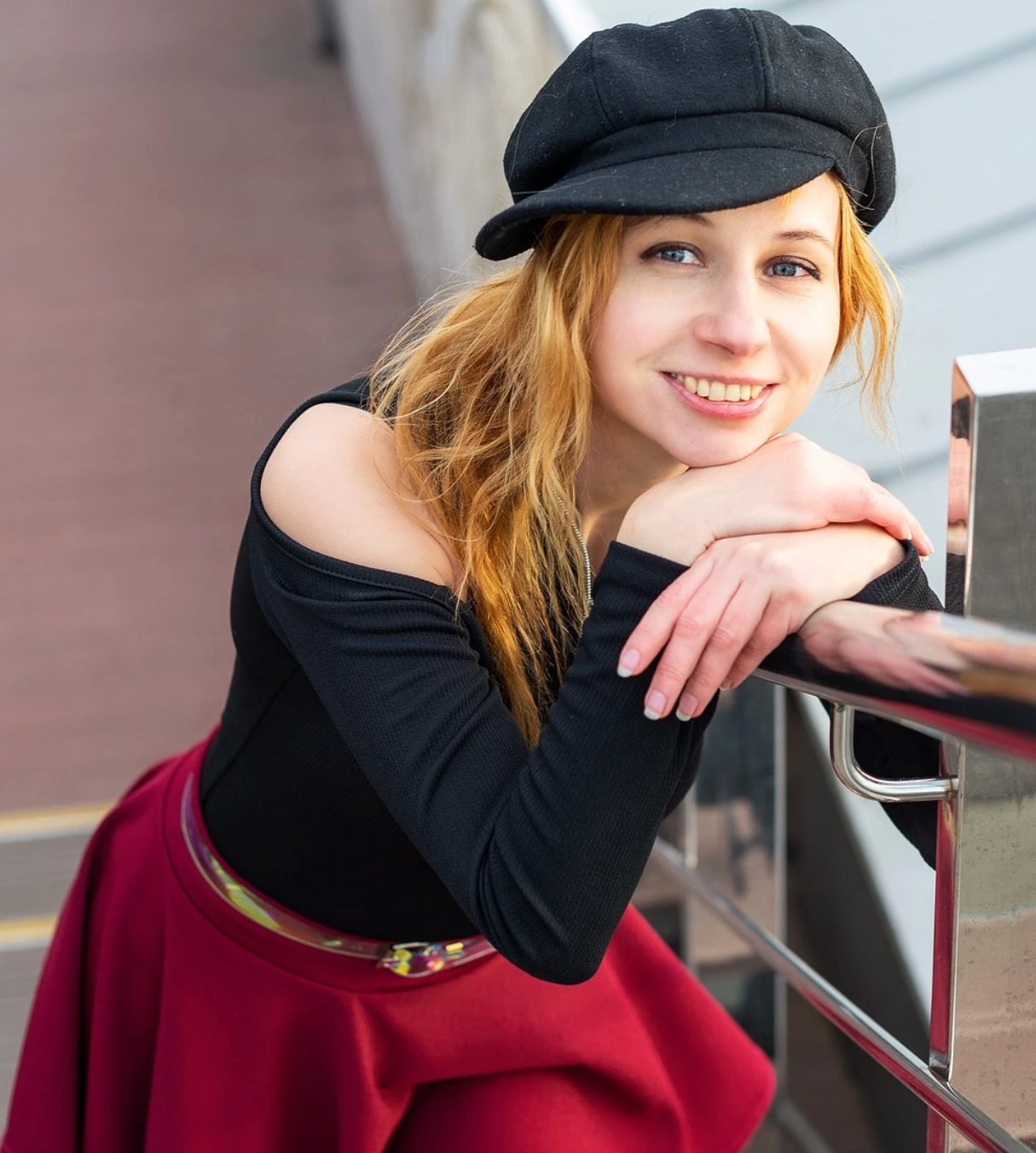 a woman on the stairs wearing black top and red skit with beret
