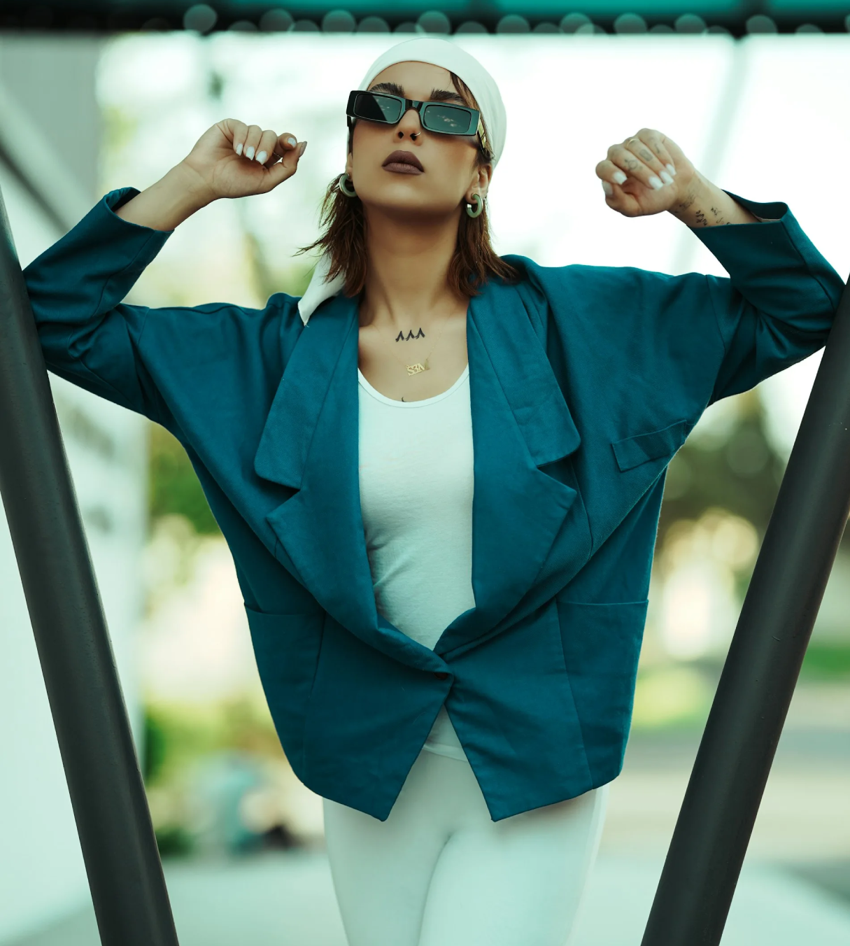 a woman wearing a blue blazer and white pants with shades