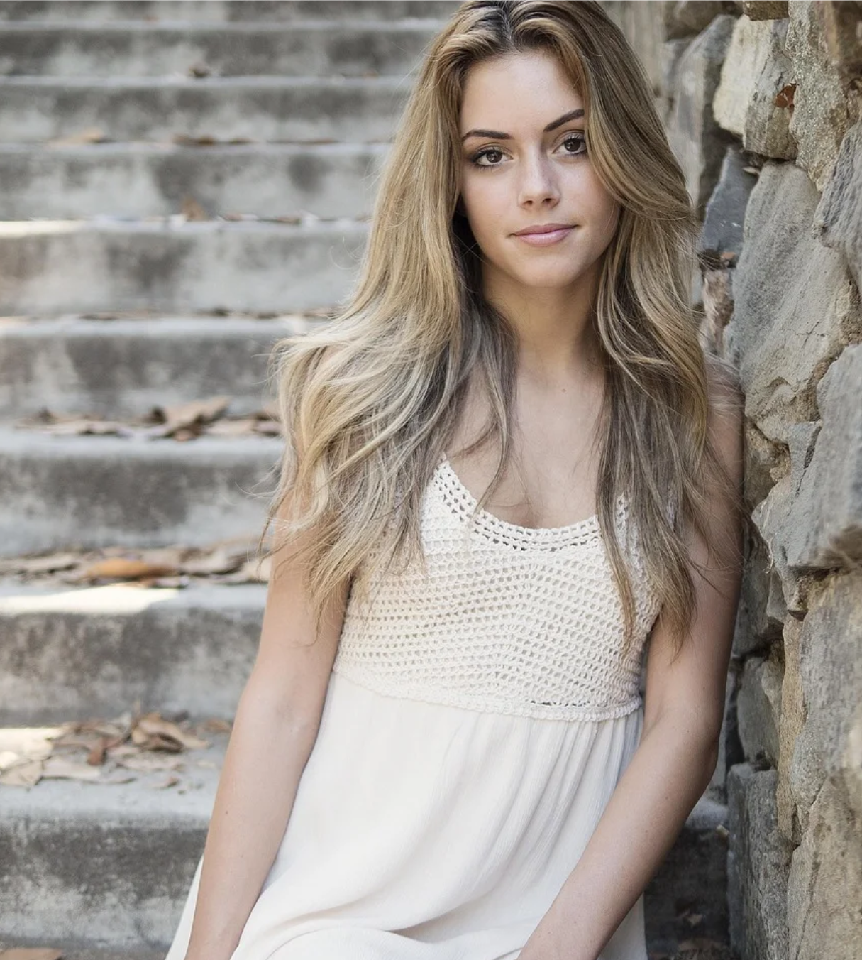 a woman standing on stone stairs in white dress
